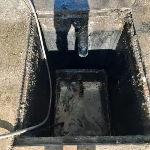 Open rectangular underground pit with hose and inlet pipe, staged for Cusco vacuum truck service.